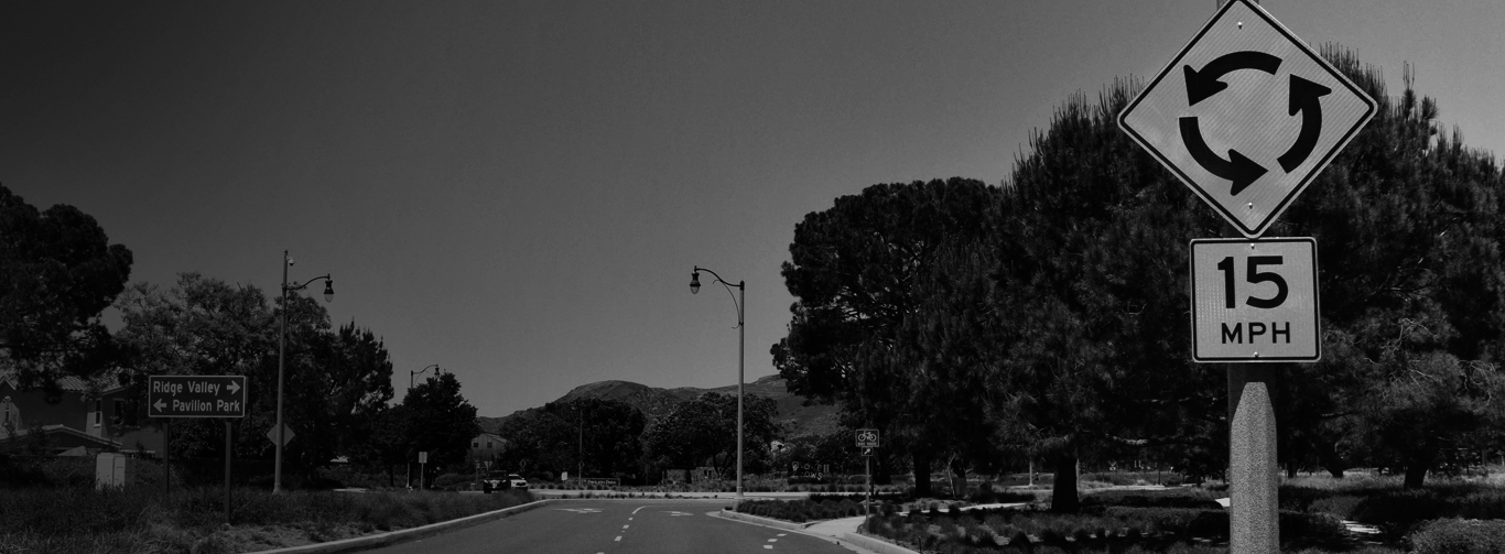 Black and White image of roundabout sign with 15 Miles Per Hour Sign